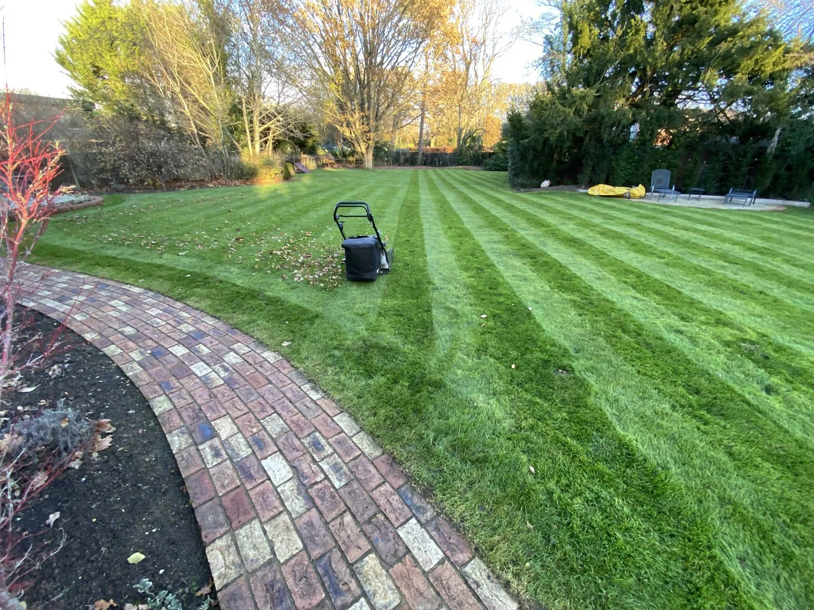 Freshly mown striped lawn beside a curved brick path - lawn mowing by Prime Outdoor Services