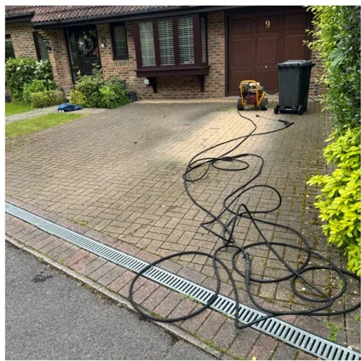 Block-paved driveway covered in green algae and moss before jet washing